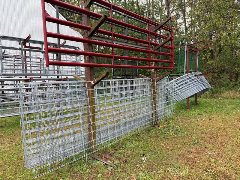 Metal livestock pens in a grassy area with trees in the background