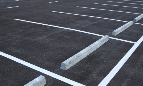 Empty parking lot with white-lined spaces and concrete bumpers.